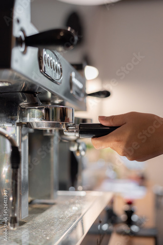 Hand working on coffee machine with blur cafe background 