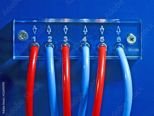 red and blue connected cables pack heap on blue transparent plexiglass control panel surface fixed with few screw closeup. color power electricity numbers concept