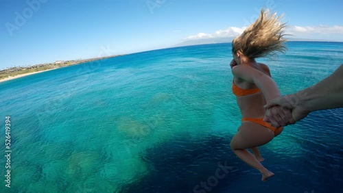 POV Couple holding hands cliff jumping into tropical ocean