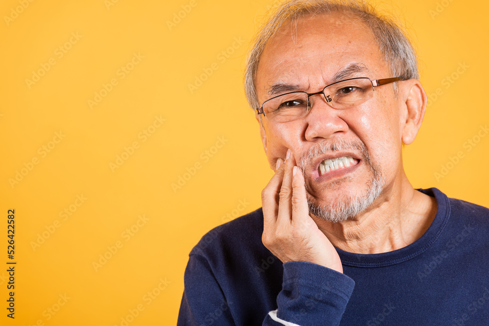 Dental pain. Portrait senior old man sad hand touching cheek suffering from toothache studio shot isolated on yellow background, Asian unhappy elder man problems with teeth pain, dental healthcare Dental pain. Portrait senior old man sad hand touching cheek suffering from toothache studio shot isolated on yellow background, Asian unhappy elder man problems with teeth pain, dental healthcare