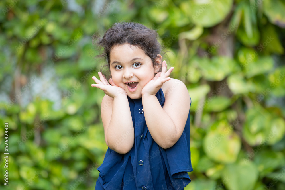 Happy cute little indian girl child with surprise expression on her face standing at park. Happy cute little indian girl child with surprise expression on her face standing at park.