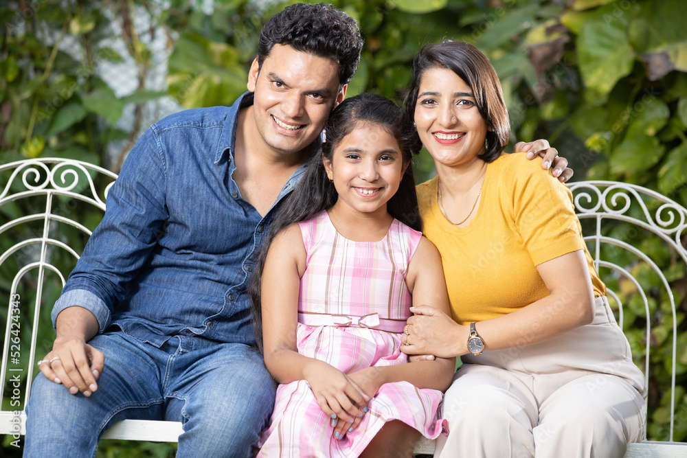 Naklejka premium Happy young indian family spending time together while sitting on hanging swing. parents with daughter.