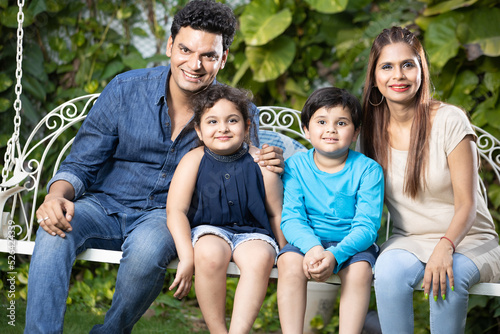 Happy young indian family pending time together while sitting on hanging swing.