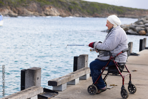 person with mobility issues sitting on wheeled walker while fishing off Bremer Bay jetty photo