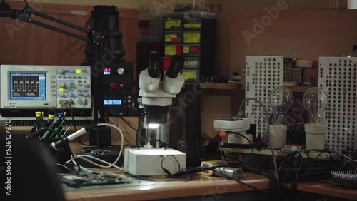 Electronics repair service workshop with soldering and diagnostics equopment. Oscilloscope, microscope and soldering iron on workspace table. photo