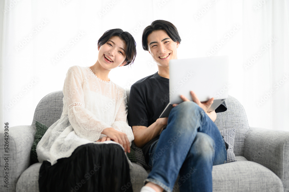 メインビジュアルにも!ソファーで座るカメラ目線のカップル メインビジュアルにも!ソファーで座るカメラ目線のカップル
