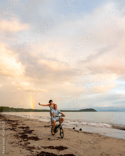 Couple riding a bike on the beach in Port Douglas.