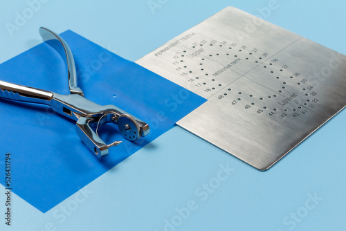 Dental hole punch, the rubber dam and the metal plate photo
