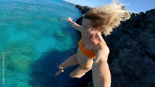 POV shot of young happy carefree woman cliff jumping into tropical blue ocean
