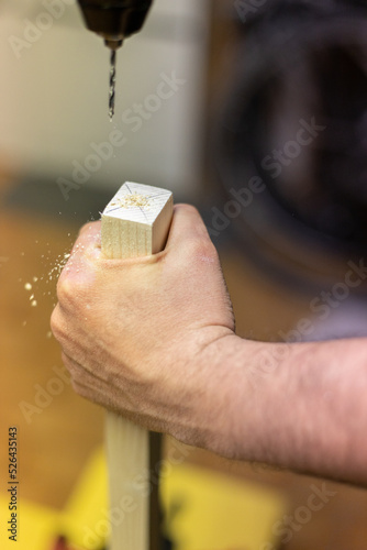 Mano con trapano che buca un pezzo di legno