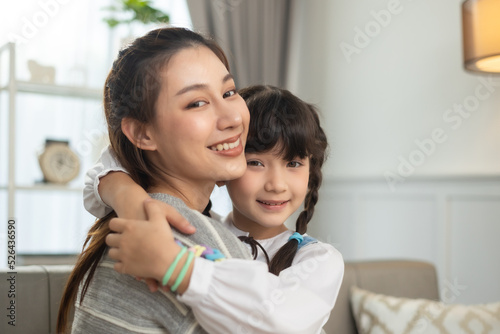 Happy Asian mother and cute little daughter having fun while playing and hugging at home in living room. Happy love family concept.