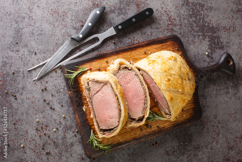 Medium Beef Wellington classic sliced steak closeup on rustic wooden board. Horizontal top view from above photo