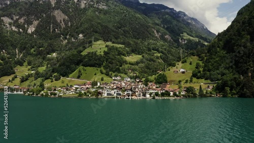 Scenic drone video, beautiful view of a modern village with a cottage development in a lowland between the Alpine mountains on the lake shore