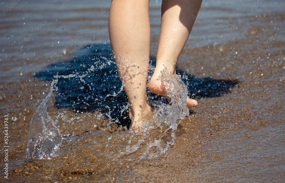 Legs of a woman walking along the shore Legs of a woman walking along the shore