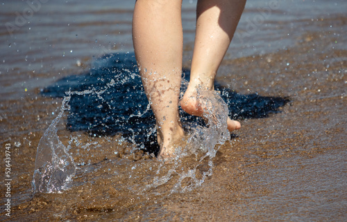 Legs of a woman walking along the shore