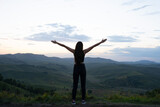 girl with hands raised up in the mountains. view of the mountain valley with the silhouette of a woman