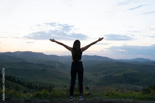 girl with hands raised up in the mountains. view of the mountain valley with the silhouette of a woman