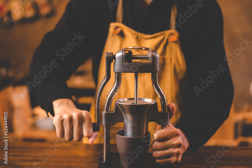 barista holding hand grinder to making beverage by grinding roasted coffee bean for caffeine drink in kitchen cafe background, morning breakfast mill preparation with espresso equipment in brown tone