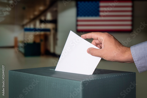 man putting electoral billuten in ballot box during elections in the usa at a polling station photo