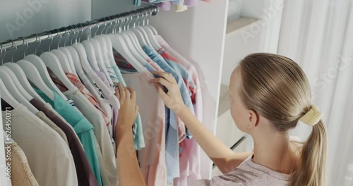A teenager chooses a dress in the dressing room. Top view