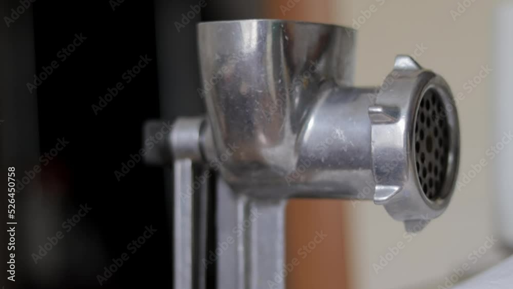 The classic manual iron meat grinder is fixed on the table. Antique, vintage meat grinder in the kitchen, close-up. The meat grinder is ready to go.