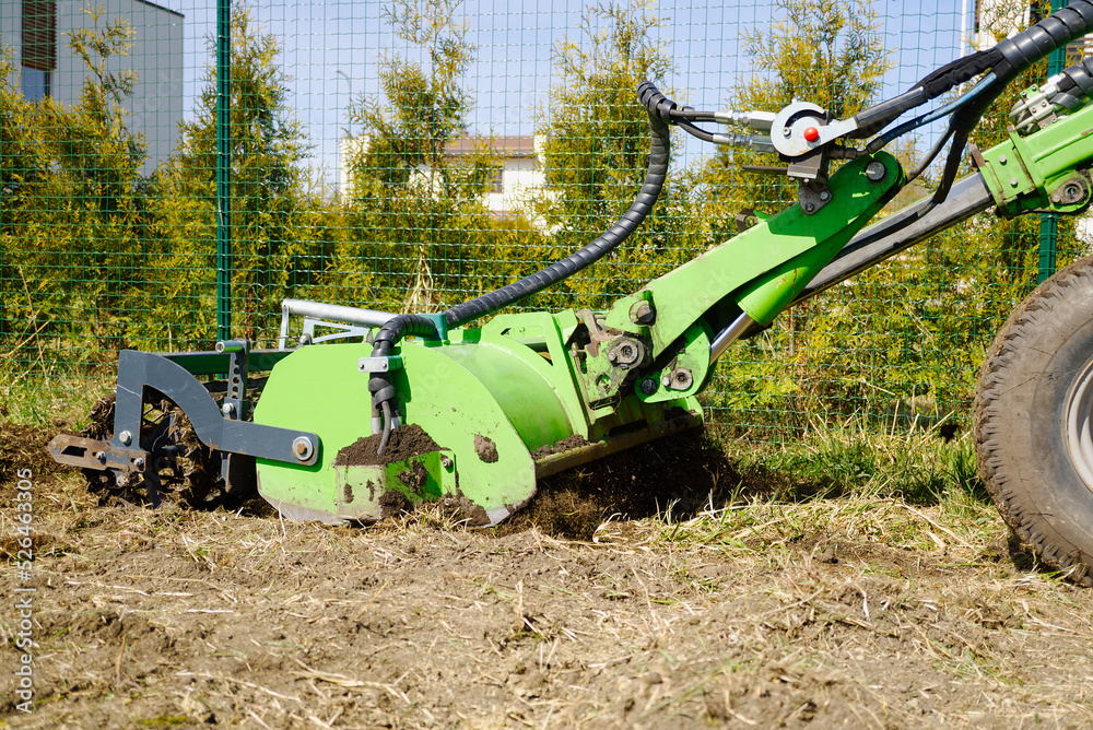 The tractor is cultivating the soil in the farm field. Freeing milling earth ground from old crops. Softening and improving soil qualities. Farming. Preparatory earthworks. Agriculture agribusiness The tractor is cultivating the soil in the farm field. Freeing milling earth ground from old crops. Softening and improving soil qualities. Farming. Preparatory earthworks. Agriculture agribusiness