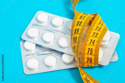 Photos Tablets in transparent plates wrapped with a centimeter tape on a blue background close-up