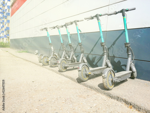 electric scooters are placed in a row at a building in the city in the sunlight. The concept of rent, electric transport, danger, business.