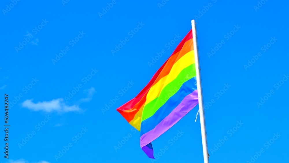 Rainbow LGBT flag on blue sky in wind. Lesbian, gay, bisexual, homosexual, transgender social movement. Concept of happiness freedom love same-sex couple, in 4K HDR Rainbow LGBT flag on blue sky in wind. Lesbian, gay, bisexual, homosexual, transgender social movement. Concept of happiness freedom love same-sex couple, in 4K HDR
