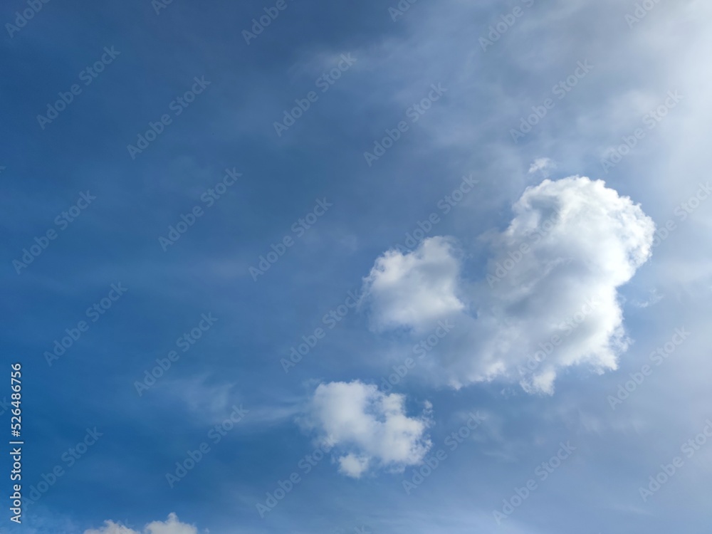 Sky with blue clouds. An autumn day, the sky is a deep blue. There are clouds in the sky at different levels. A white fluffy cumulus cloud of an interesting shape moves slowly. Sky with blue clouds. An autumn day, the sky is a deep blue. There are clouds in the sky at different levels. A white fluffy cumulus cloud of an interesting shape moves slowly.