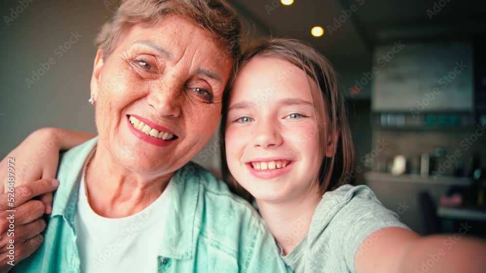 A cheerful couple of grandmother and her granddaughter are taking a selfie together. A cheerful couple of grandmother and her granddaughter are taking a selfie together.