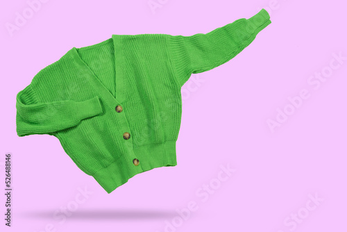 Green knitted sweater, sleeves to the side, as if indicating information, concept, on a lilac background