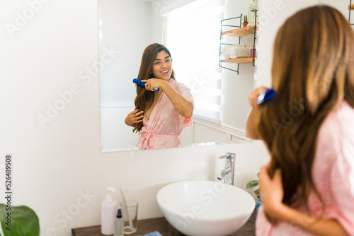 Rear view of a cheerful woman brushing her hair in the bathroom
