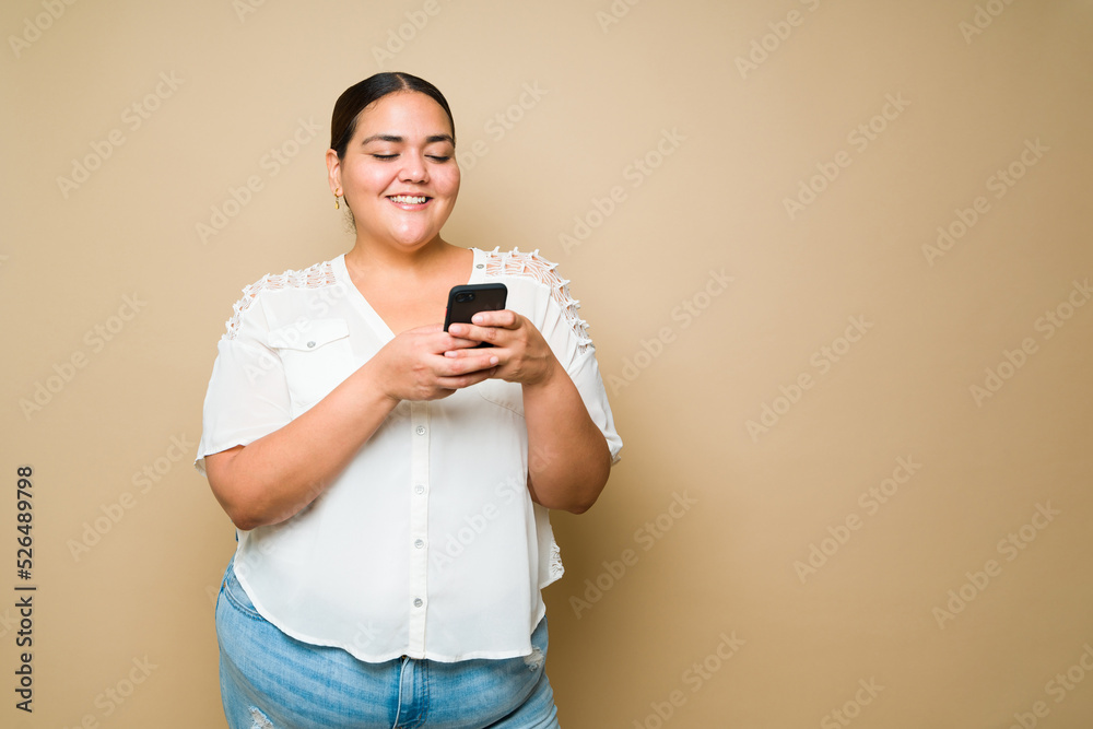Excited plus size woman sending a text message on her smartphone Excited plus size woman sending a text message on her smartphone