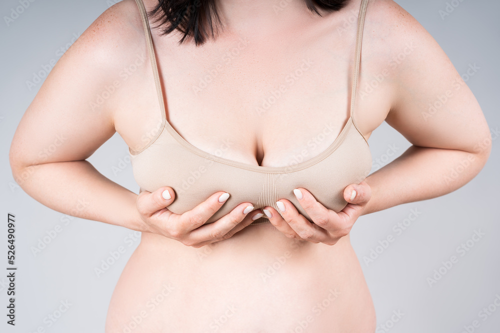 Breast test, woman in beige bra examining her breasts for cancer on gray  background Stock Photo