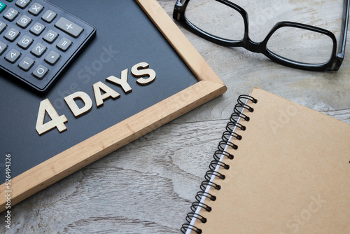 4 days work week concept with letters on the black chalkboard, a calculator, eyeglasses, and a notebook
