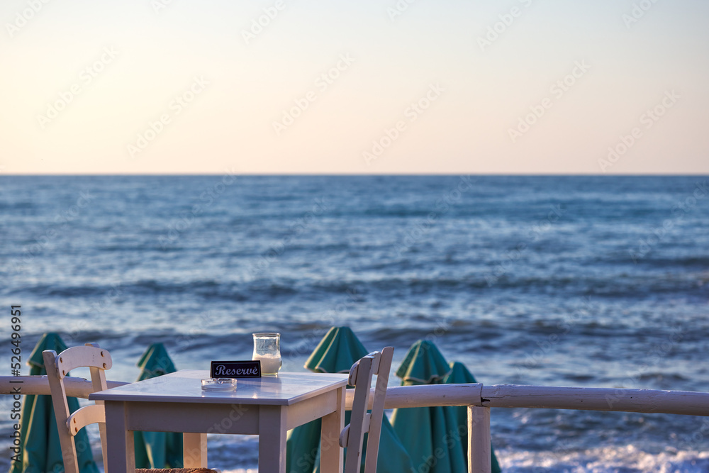 Obraz premium Empty reserved table at a greek taverna and the sea in background