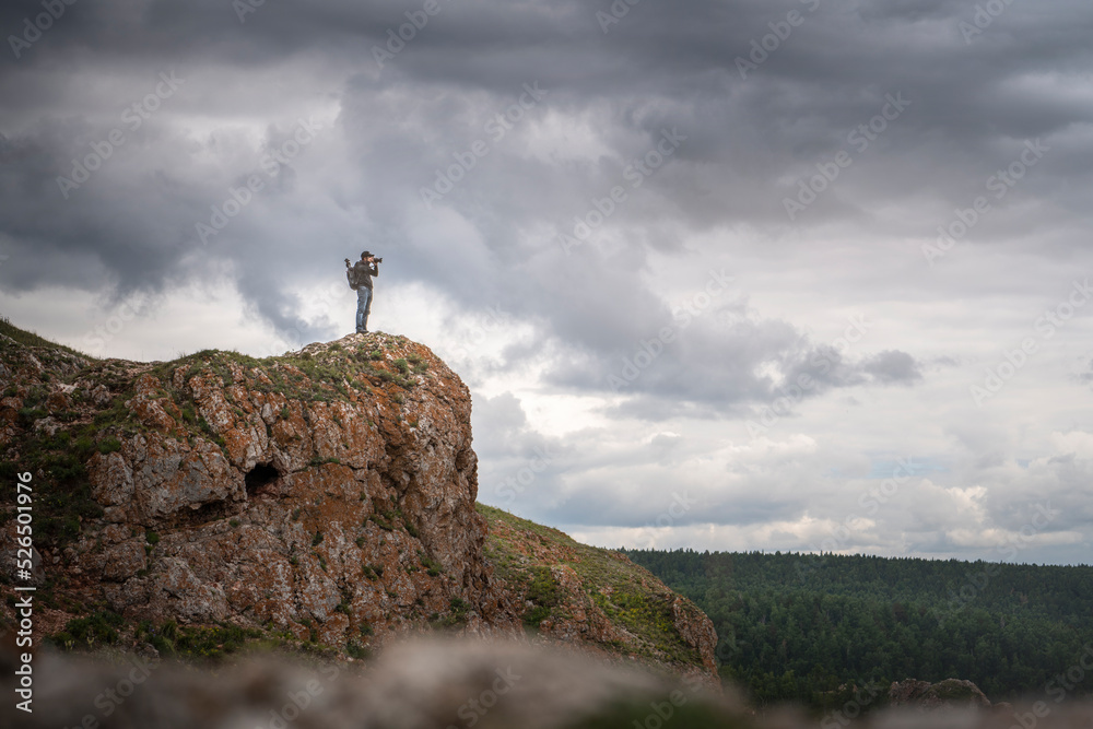 a traveler travel photographer on top of a mountain photographs nature landscape. Landscape photography against the sky copy space