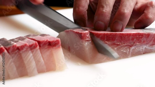 和食レストランの厨房で、熟練の職人が包丁で丁寧に切り分ける新鮮なカンパチの刺身。シズル感あふれる調理シーンの動画素材