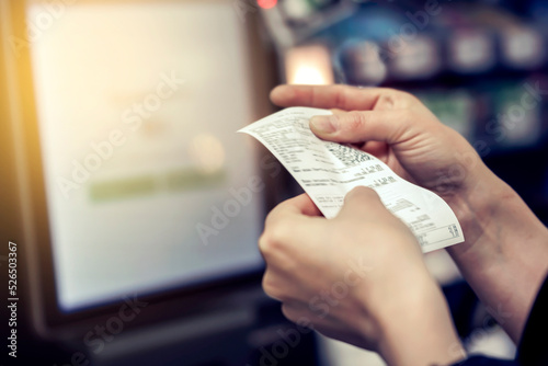 the girl looks at the receipt in the store photo