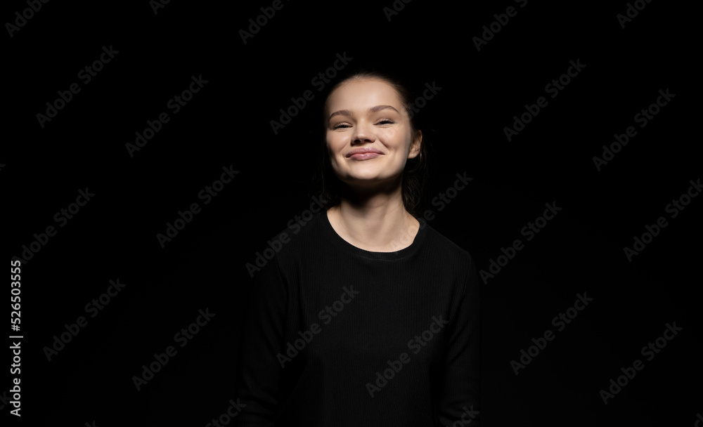 Naklejka premium Portrait of emotive good-looking brunette woman looking in a camera and standing against black background.
