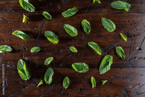 Background and texture from mint leaves. Mint leaves are scattered on the table. Hard light. Deep shadow. © vzwer