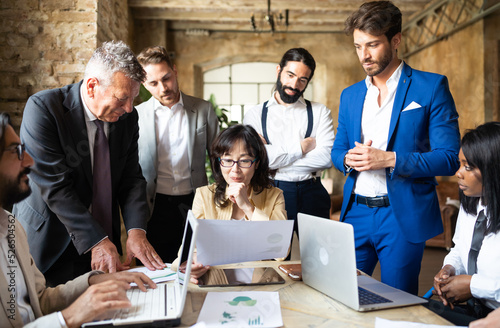 Authoritative business woman consulting his international team to facing the energy global crisis - Group of multiethnic people working on renewable and sustainable power photo