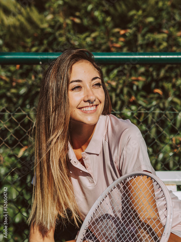 mujer joven sentada con una raqueta de tenis