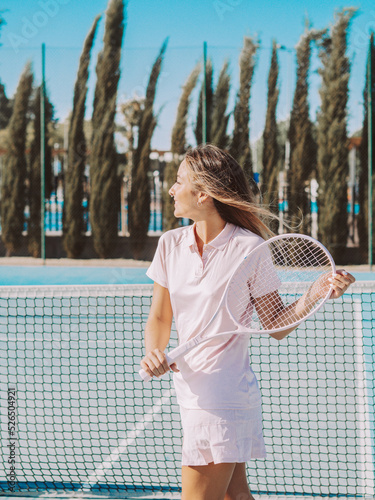 Mujer joven sonriente usando una raqueta de tenis en una pista de tenis al aire libre durante las vacaciones de verano © David Martínez