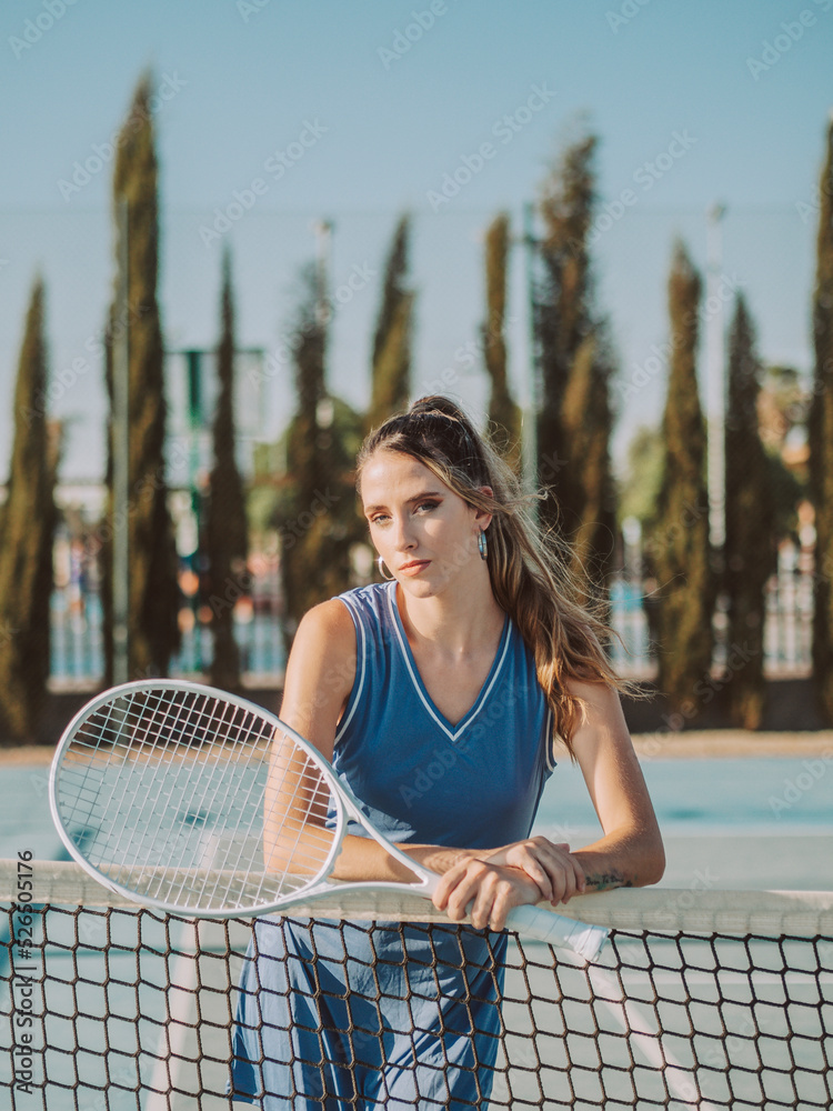 Mujer joven y guapa en una pista de tenis con una raqueta de tenis.