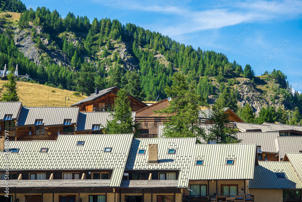 Chalets and roofs of mountain residences in a ski resort in summer. Southern Alps, France.