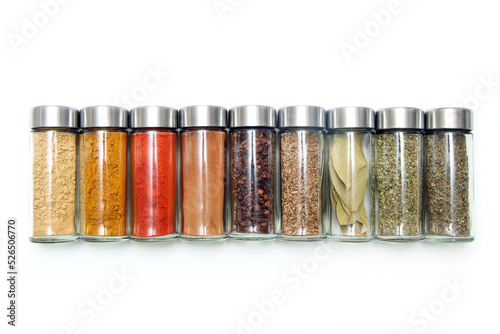 The different types of spices and herbs stored inside the small closable glass bottle isolated on a white background. 
