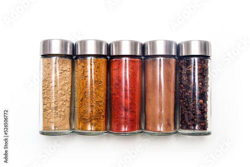 The different types of spices and herbs stored inside the small closable glass bottle isolated on a white background. 