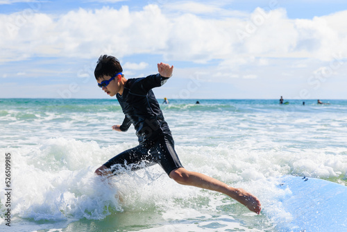 Young boy, a new student in surfing, loses his grip and falls from a surfboard into the water during class.